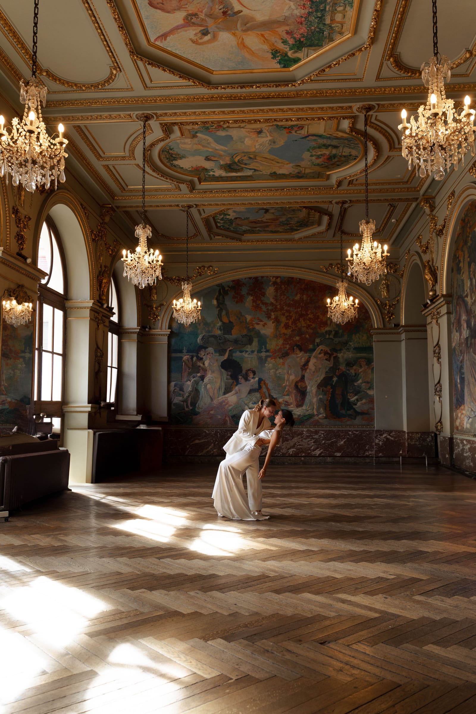 Dans une immense salle dorée du Capitole de Toulouse, une mariée renverse l’autre pour un baiser, dans un rai de soleil.